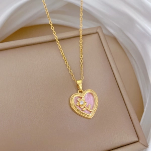 Detail of gold heart pendant with pink enamel and sparkling crystals on silk fabric