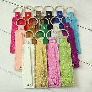 Macro view of assorted 8mm metallic sequin keychains with rivets on white wood background
