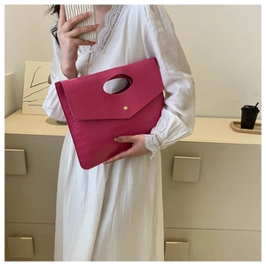 Detail of fuchsia crocodile texture tote bag with metal snap button held by model
