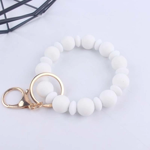 Dettaglio del braccialetto in perle di silicone bianco con anello dorato e moschettone