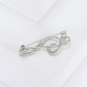 Macro detail of a silver music note brooch with textured pavé finish on white blocks