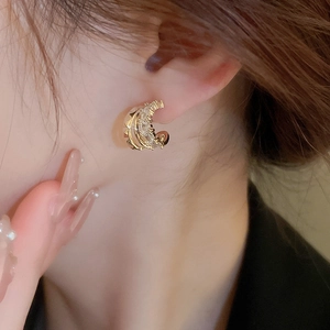 Close-up of gold C-shaped earring with zircon stones worn by a model for a stylish look