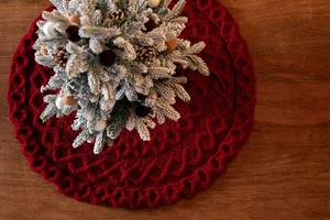 Détail de la jupe de sapin de Noël tricotée rouge avec motifs de torsades losanges