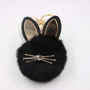 Detail of a fluffy black cat pom-pom keychain with golden ears and lobster clasp hook