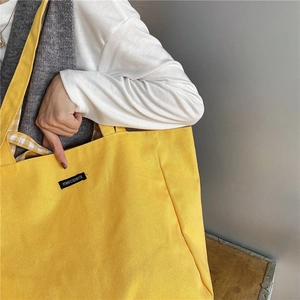 Macro view of bright yellow canvas tote bag showing thick fabric and merciparis label