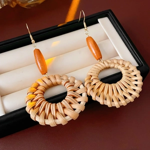 Gros plan détaillé de boucles d'oreilles bohèmes en rotin avec perles en bois sur velours