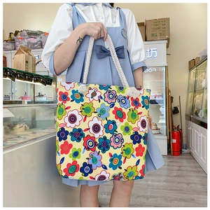 Floral canvas tote bag with white rope handles carried by a model in a bright boutique shop