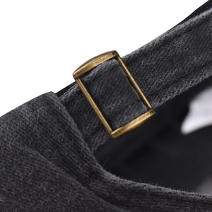 Detail of adjustable brass buckle and cotton fabric on dark grey baseball cap