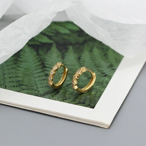 Macro shot of gold hoop earrings with clear cubic zirconia on a minimalist background
