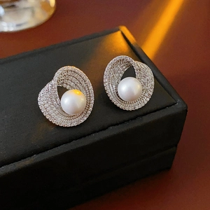 Gros plan détaillé d'une boucle d'oreille perle avec spirale en zircon sur cuir noir de luxe