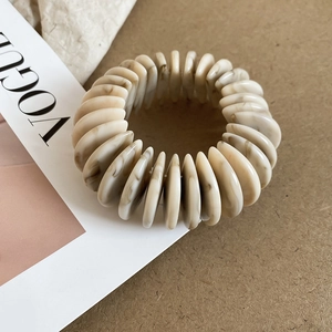 Detail of marble pattern acrylic beads on an elastic bracelet over a fashion magazine