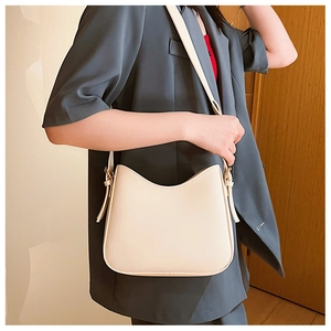 Detailed view of cream-colored PU leather shoulder bag worn by model in minimalist setting