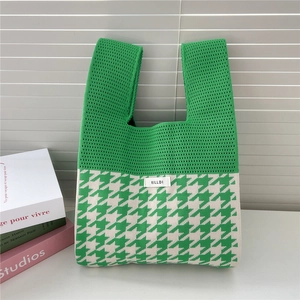 Detail of green and white houndstooth knit tote bag with brand label and soft texture