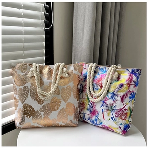 Detail of canvas tote bags with thick rope handles featuring gold leaf and palm tree prints