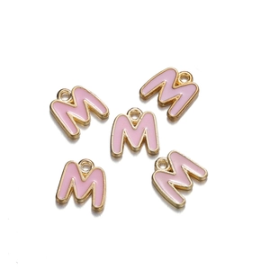 Detail of pink enamel letter M charms with gold alloy frames for DIY jewelry making