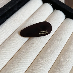 Gros plan d'une pince à cheveux marron foncé avec logo France Handmade doré gravé