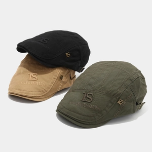 Close-up of vintage cotton newsboy caps in black, khaki and green with metal logo