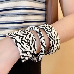 Detail of zebra print leather bracelets featuring wide pleated and thin braided styles