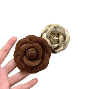 Brown flocked camellia flower brooch with gold metallic accents shown against white background