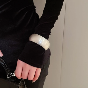 Close-up of wide matte silver oval bangle featuring a brushed metal texture on a black sleeve