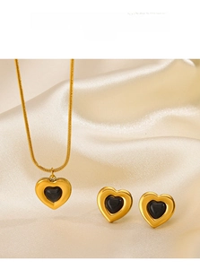 Detail of heart jewelry set with black gemstones on champagne satin background