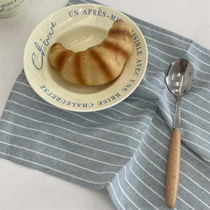 Vue détaillée d'une assiette en céramique crème avec texte bleu et cuillère en bois