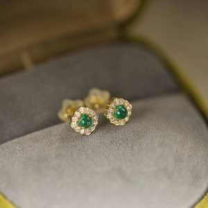 Macro detail of S925 silver gold floral stud earrings with emerald stone and tiny diamonds