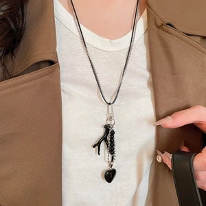 Detail of layered black heart pendant necklace with beads on silver ball chain and leather