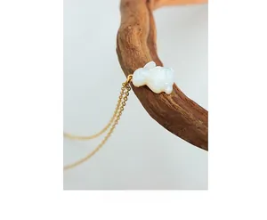 Macro d'un pendentif lapin en or 18 carats avec finition nacre sur branche