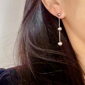 Detail of silver long chain earrings with three polished spheres on a model