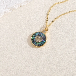 Détail d'un collier doré avec mosaïque de nacre bleue et zircon en forme de cœur brillant