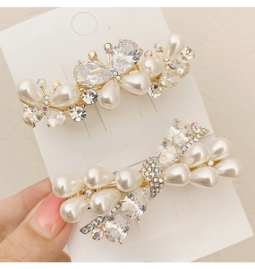 Detailed macro view of crystal butterfly hair clips with glossy pearls and gold metal base