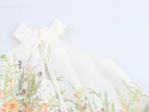 Détail du haut dos nu blanc avec imprimés floraux et col à nouer délicat et élégant