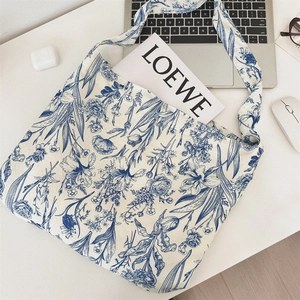 Flat lay of vintage blue floral cotton tote bag with white office stationery and laptop
