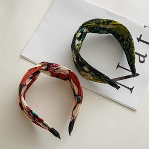 Detailed view of wide fabric headbands featuring red floral and green vintage patterns