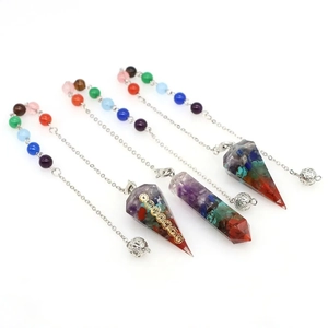 Set of four 7 chakra resin crystal pendulums with silver metal chains on white background