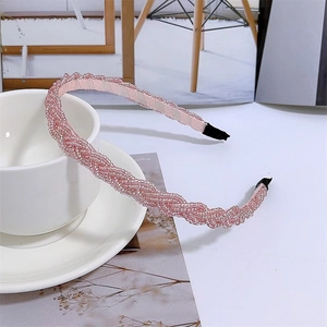 Pink pearl-beaded braided headband displayed on a magazine with a white ceramic cup