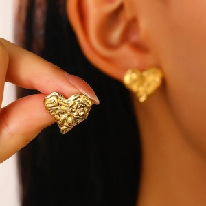 Detail of heart-shaped 18K gold earrings featuring a unique crumpled metal texture finish