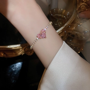 Macro view of gold plated bracelet featuring pink heart shaped stones and zircon details