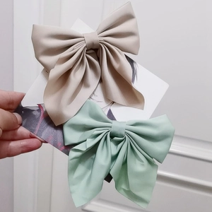Detail of beige and mint green fabric bow hair clips held on a display card