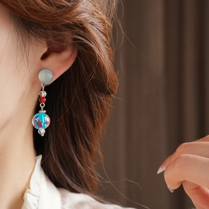 Close-up of glass bead earrings featuring a blue sphere with a delicate red goldfish pattern