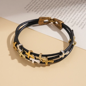 Détail d'un bracelet en cuir multicouche avec des croix en métal bicolore et fermoir magnétique
