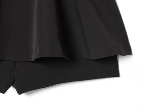 Detail van de zwarte gelaagde rokzoom met fijne stiksels en een matte textuur