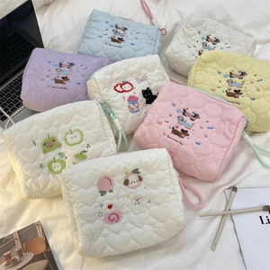 Macro shot of quilted heart texture and various cute animal embroidery on makeup bags