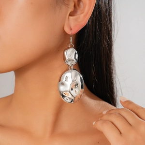 Macro shot of silver oversized irregular geometric earrings with hammered texture