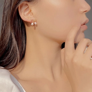 Gros plan de boucles d'oreilles nœud doré avec perles sur modèle au style élégant