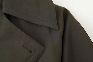 Détails de la texture du sergé haute densité et des coutures sur le revers du manteau olive