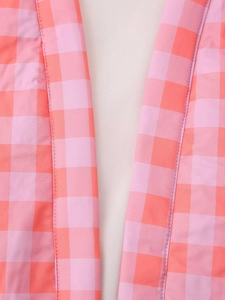 Detailed close-up of pink and orange plaid fabric showing texture and stitching on the outfit
