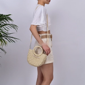 Detail showing handwoven natural straw texture and white shell decoration on the bag