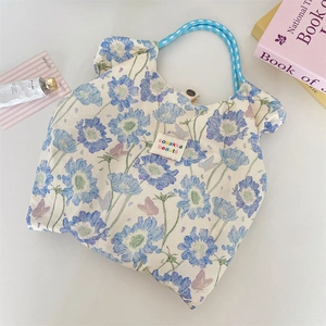 Detailed shot of floral canvas tote bag with woven blue handles and snap button closure